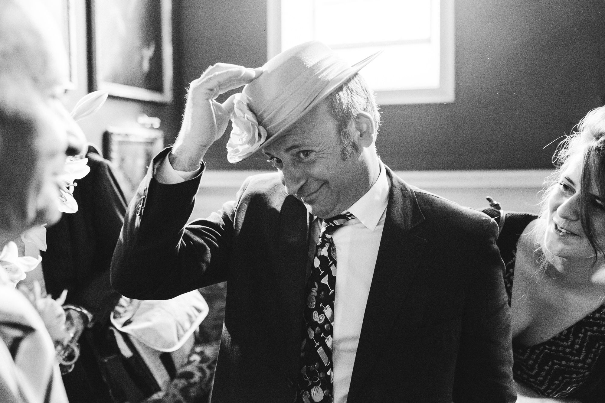 Happy wedding guest playing with a womens hat