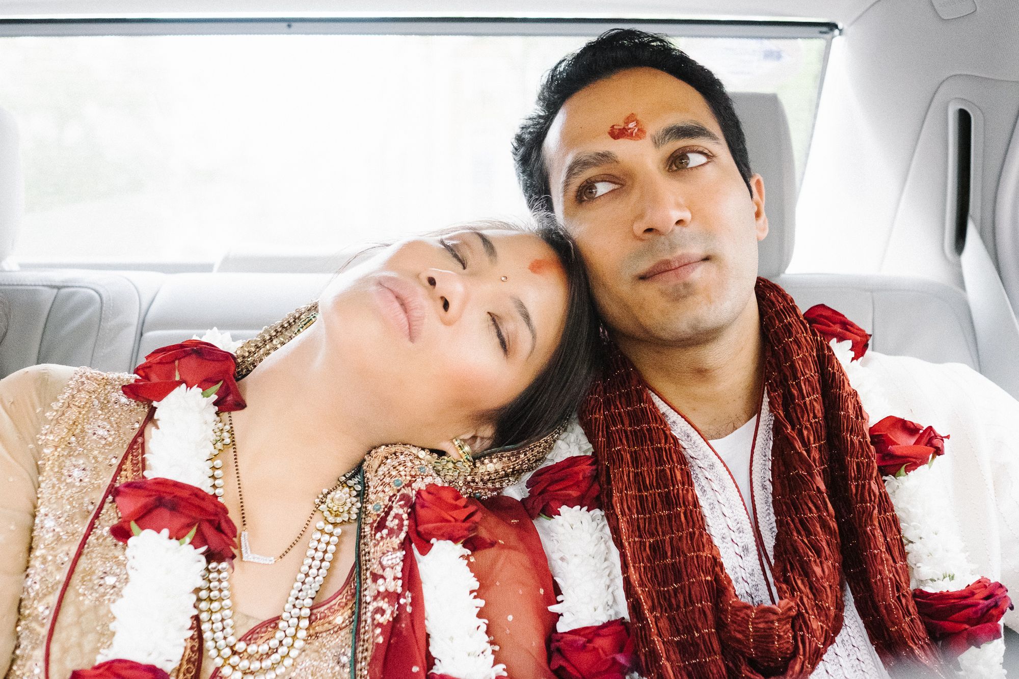 Chinese bride and Indian groom in car after Hindu wedding ceremony
