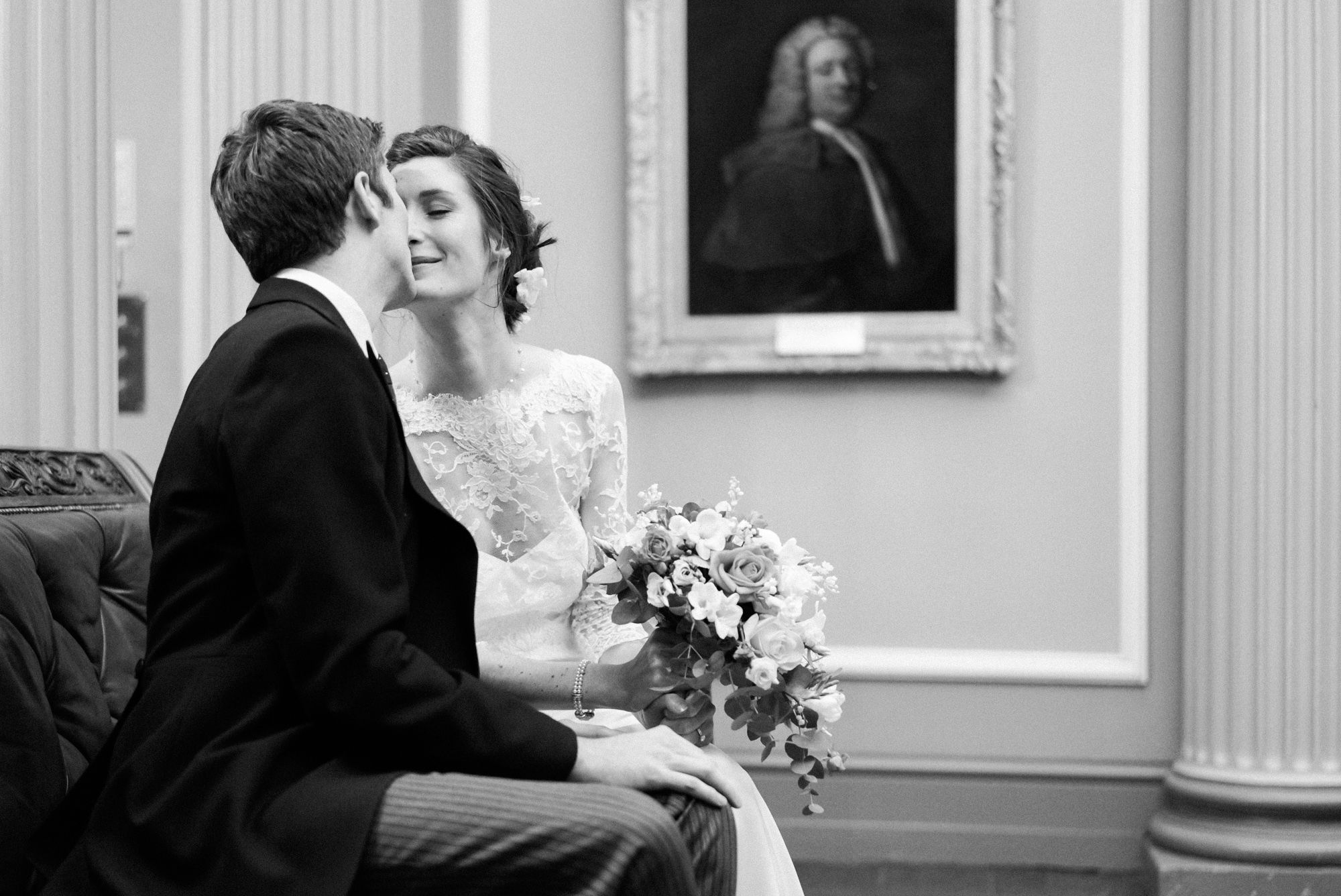 Bride and groom kissing on a sofa at The Signet Library
